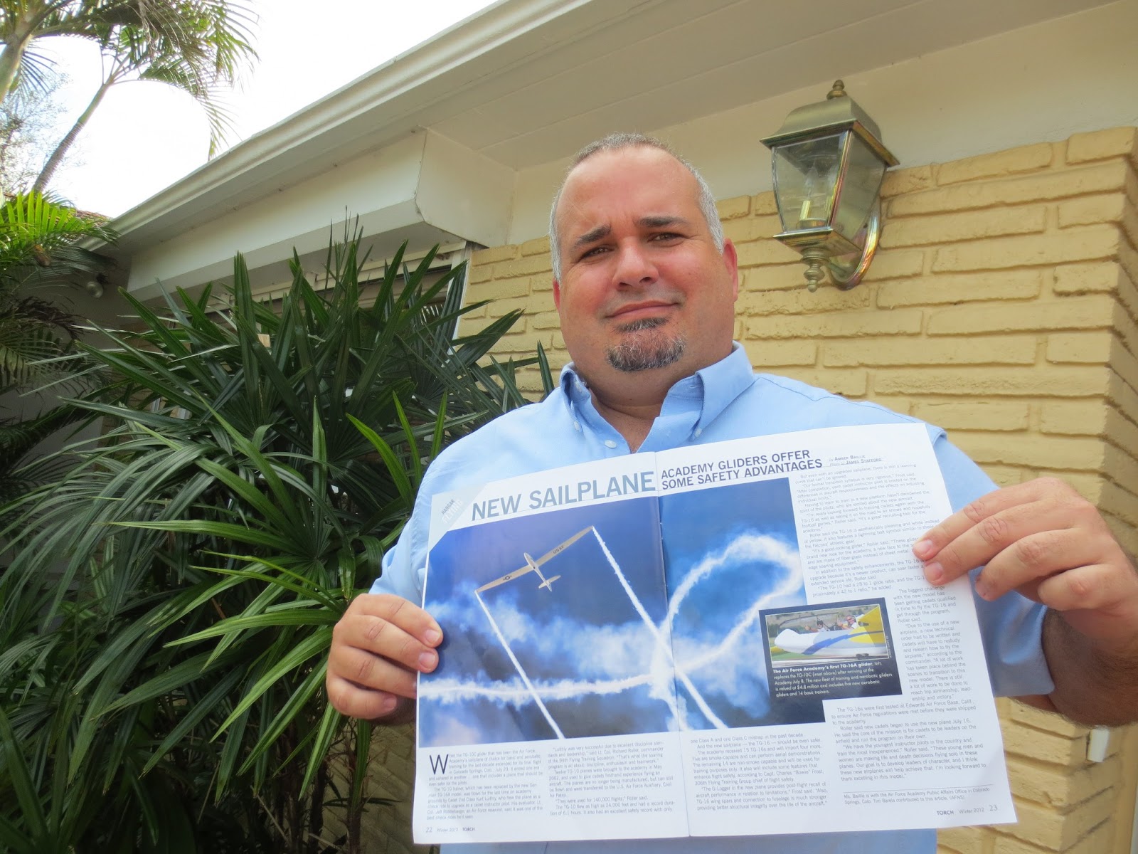 James "Jim" Stafford holding the issue of TORCH featuring his photo blue sky sailing
